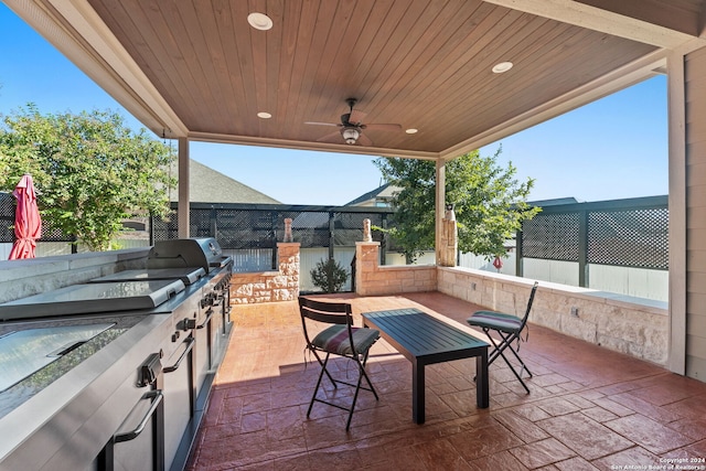 view of patio featuring a ceiling fan, fence, and exterior kitchen