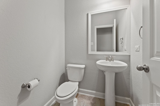 half bath featuring baseboards, a textured wall, toilet, wood finished floors, and a sink