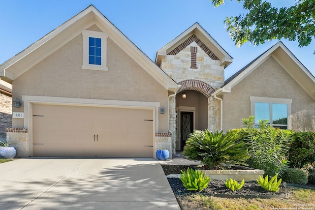 view of front facade featuring a garage, stone siding, concrete driveway, and stucco siding