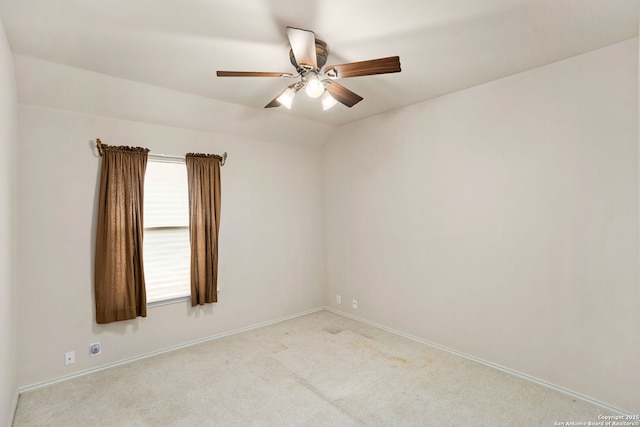 carpeted spare room featuring lofted ceiling, ceiling fan, and baseboards