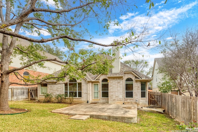 back of property with brick siding, a patio, a shingled roof, a lawn, and a fenced backyard