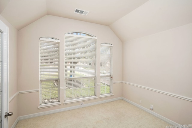 carpeted spare room with lofted ceiling, visible vents, and baseboards