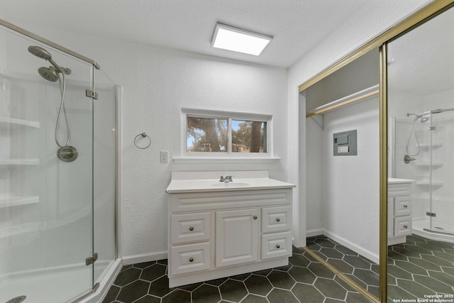 bathroom with a stall shower, a textured wall, tile patterned floors, a textured ceiling, and vanity