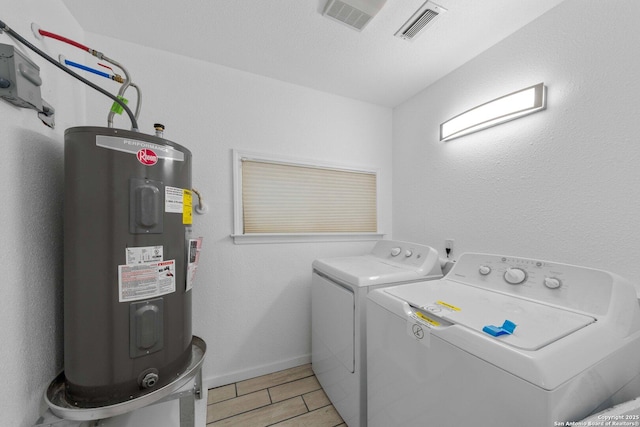 clothes washing area with laundry area, visible vents, baseboards, water heater, and independent washer and dryer