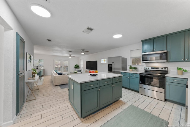 kitchen with stainless steel appliances, light countertops, a kitchen island, and green cabinets