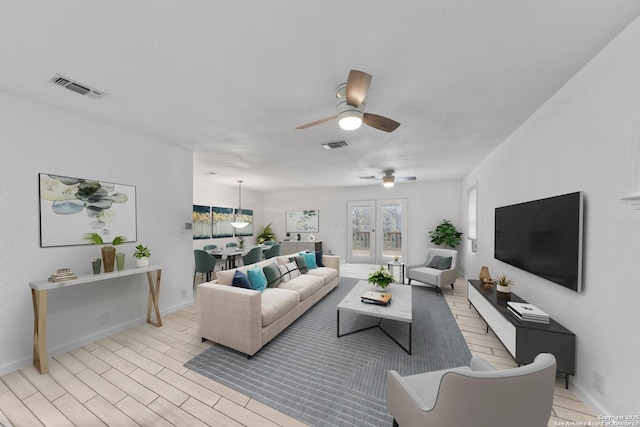 living room with baseboards, light wood-style flooring, visible vents, and a textured ceiling