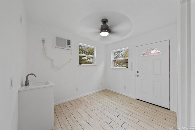 laundry area featuring ceiling fan, a sink, light wood-style flooring, and baseboards