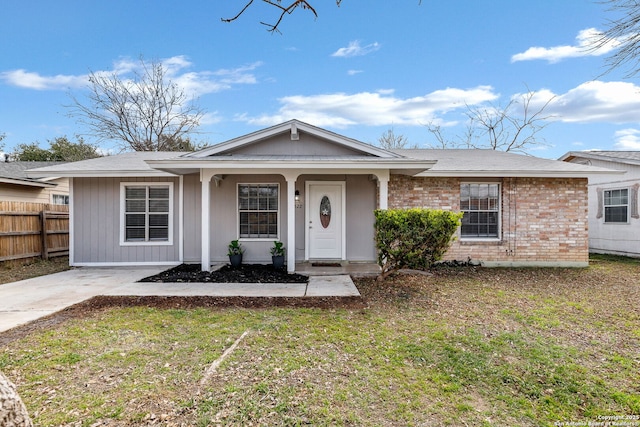 view of front of property with brick siding, fence, and a front lawn