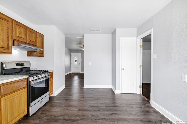 kitchen featuring baseboards, visible vents, dark wood-style flooring, under cabinet range hood, and gas stove