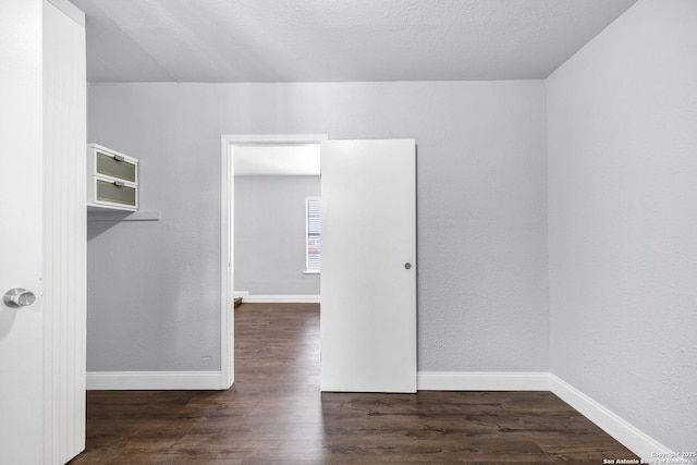 spare room with a textured wall, wood finished floors, and baseboards