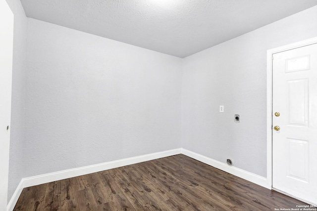 empty room with dark wood finished floors, a textured ceiling, and baseboards