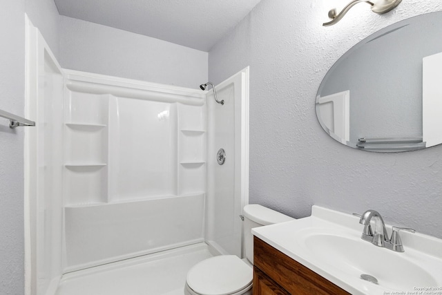 full bathroom with a stall shower, a textured wall, vanity, and toilet