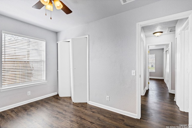 unfurnished bedroom with baseboards, dark wood-type flooring, and a textured wall