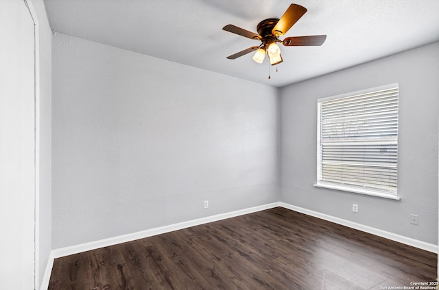 spare room with dark wood finished floors, baseboards, and ceiling fan