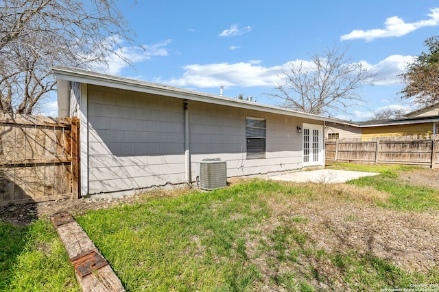 rear view of property with a lawn, a patio, fence, cooling unit, and french doors