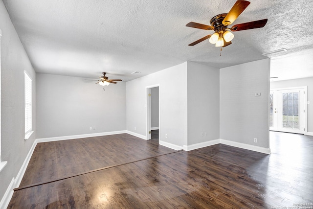 unfurnished room featuring a textured ceiling, ceiling fan, dark wood-type flooring, visible vents, and baseboards