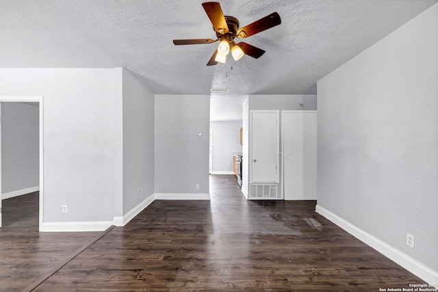 empty room with dark wood-style flooring, visible vents, ceiling fan, a textured ceiling, and baseboards