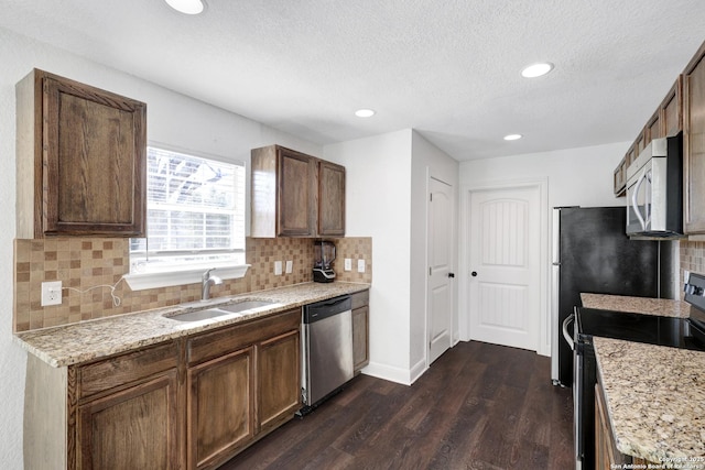 kitchen featuring a sink, baseboards, appliances with stainless steel finishes, decorative backsplash, and dark wood finished floors