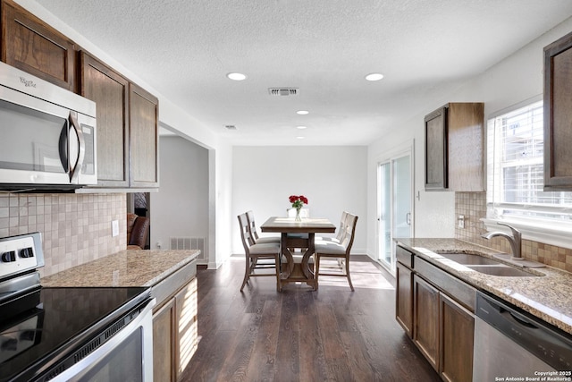 kitchen with appliances with stainless steel finishes, dark wood-style flooring, visible vents, and a sink