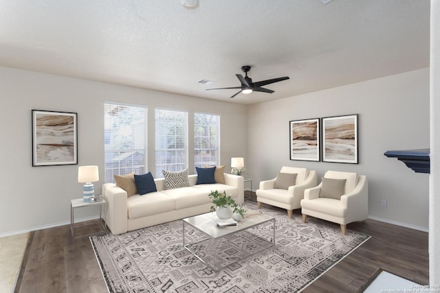 living area with a ceiling fan, visible vents, baseboards, and wood finished floors