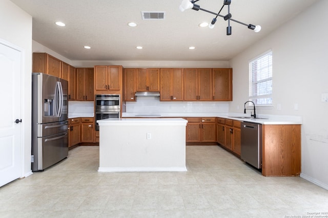 kitchen featuring stainless steel appliances, light countertops, visible vents, a sink, and under cabinet range hood