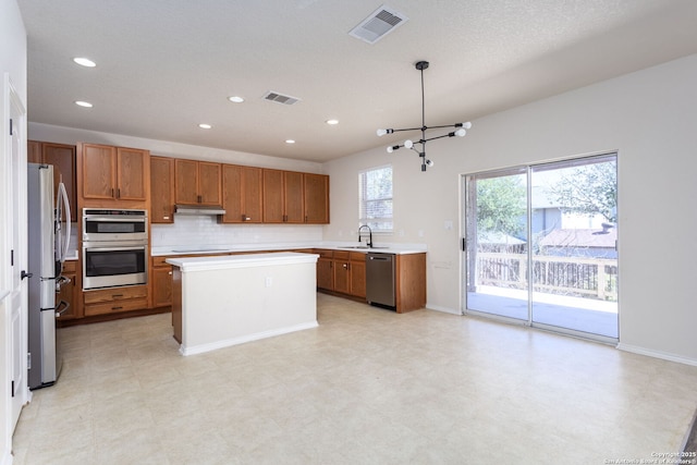 kitchen featuring visible vents, brown cabinetry, stainless steel appliances, light countertops, and a sink