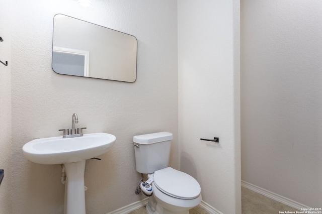 half bath featuring toilet and baseboards