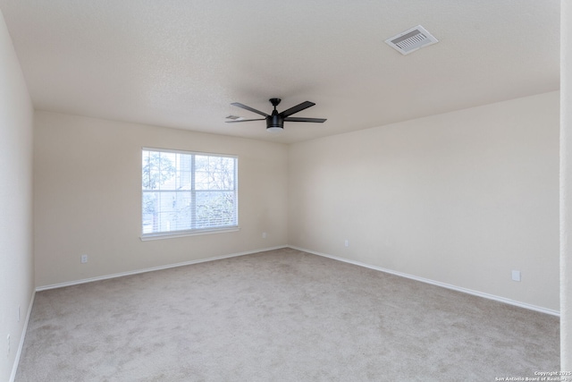 empty room with carpet floors, ceiling fan, visible vents, and baseboards