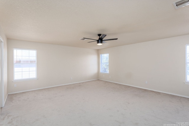 unfurnished room featuring light carpet, baseboards, visible vents, ceiling fan, and a textured ceiling