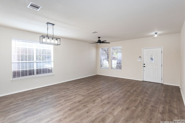 unfurnished living room with baseboards, visible vents, and wood finished floors