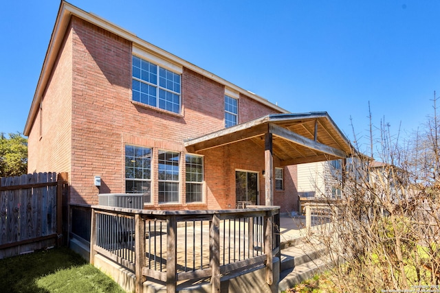 back of property featuring central AC unit, fence, a deck, and brick siding