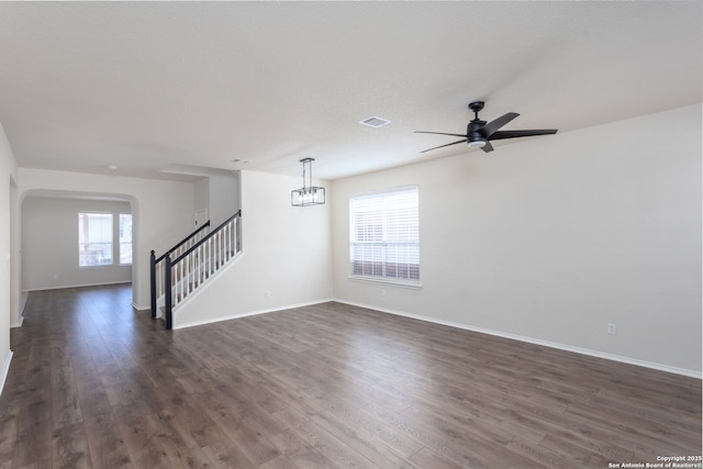 unfurnished room with dark wood-style floors, visible vents, stairway, and baseboards