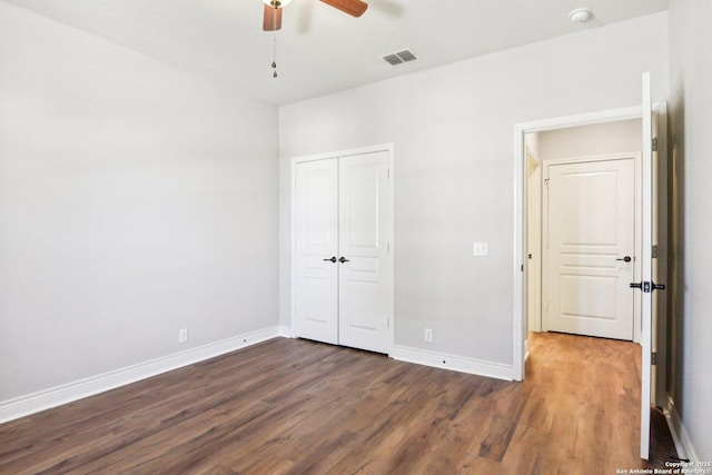 unfurnished bedroom with a closet, visible vents, baseboards, and wood finished floors