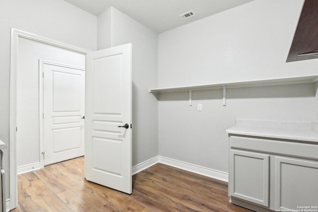 laundry area featuring wood finished floors, visible vents, and baseboards