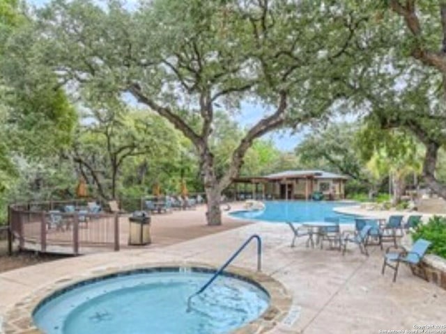 community pool with a patio and a hot tub