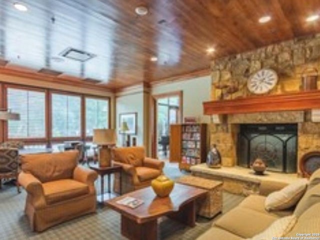 living room featuring wood ceiling, visible vents, and a stone fireplace