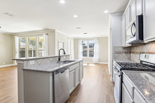 kitchen featuring stainless steel appliances, a sink, backsplash, and ornamental molding