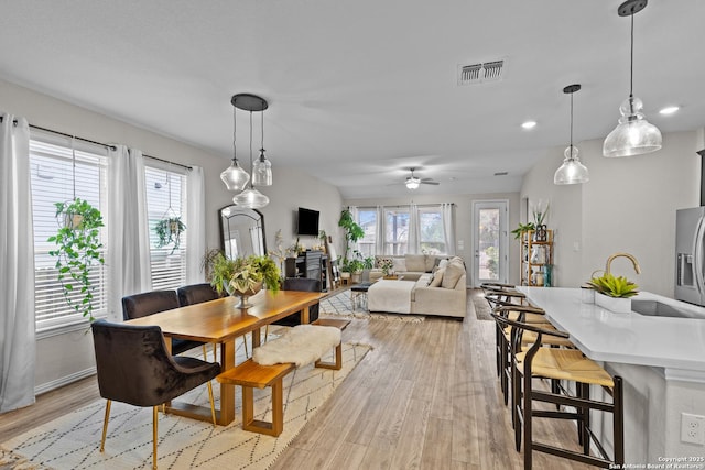 dining room with light wood-type flooring, visible vents, and a healthy amount of sunlight