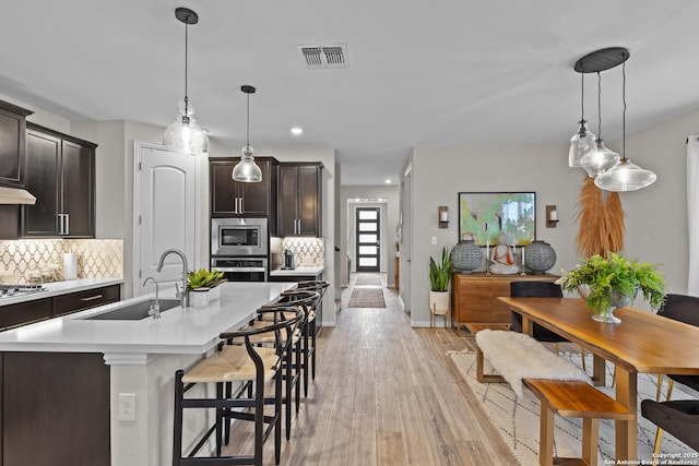 kitchen featuring stainless steel appliances, light countertops, visible vents, backsplash, and a sink