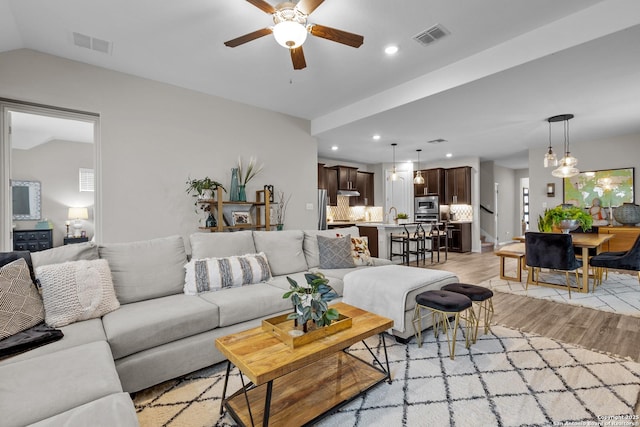 living room with light wood-type flooring, visible vents, vaulted ceiling, and recessed lighting