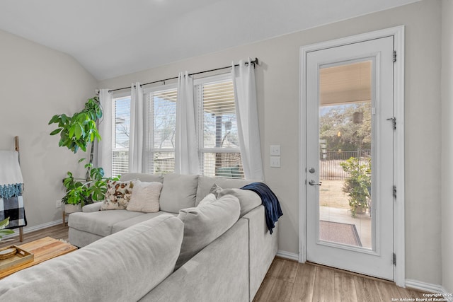 living area featuring light wood-style floors, baseboards, and vaulted ceiling