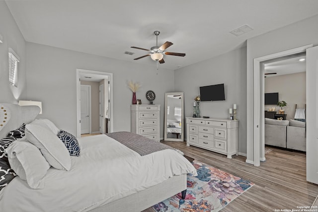 bedroom with light wood-style floors, visible vents, and ceiling fan