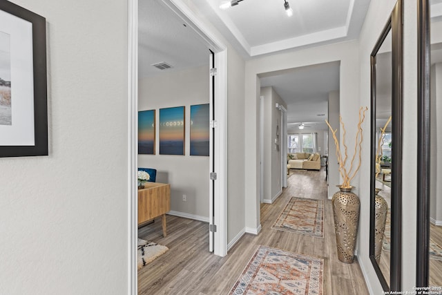 hallway featuring visible vents, baseboards, and wood finished floors