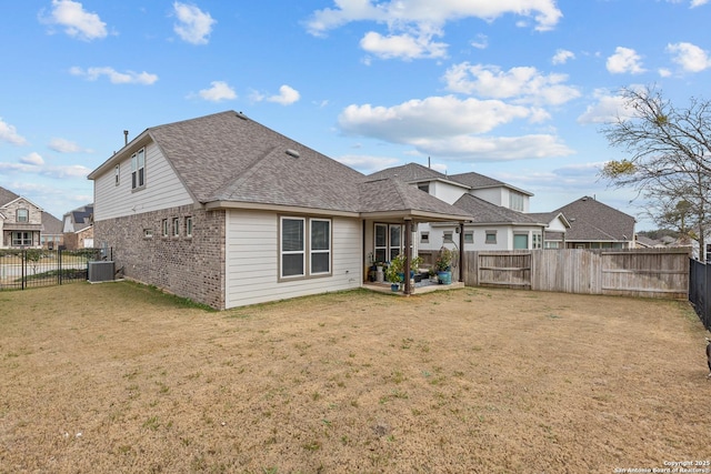 back of house with brick siding, a lawn, central AC unit, and a fenced backyard