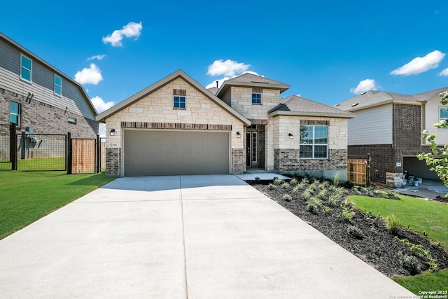 view of front facade with driveway, an attached garage, fence, a front yard, and brick siding