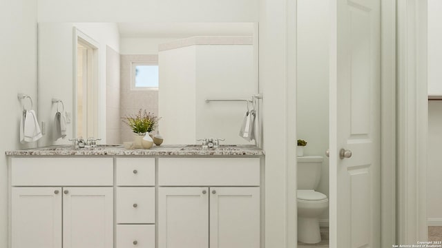 full bath featuring double vanity, a sink, and toilet