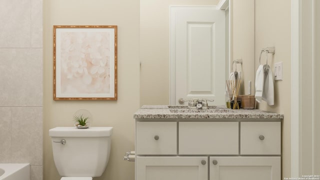 bathroom featuring toilet, a bath, and vanity