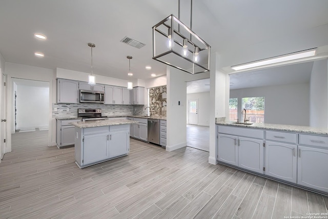 kitchen with a sink, visible vents, appliances with stainless steel finishes, backsplash, and wood tiled floor