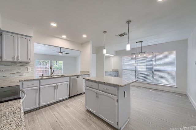 kitchen featuring visible vents, dishwasher, backsplash, wood finish floors, and a sink