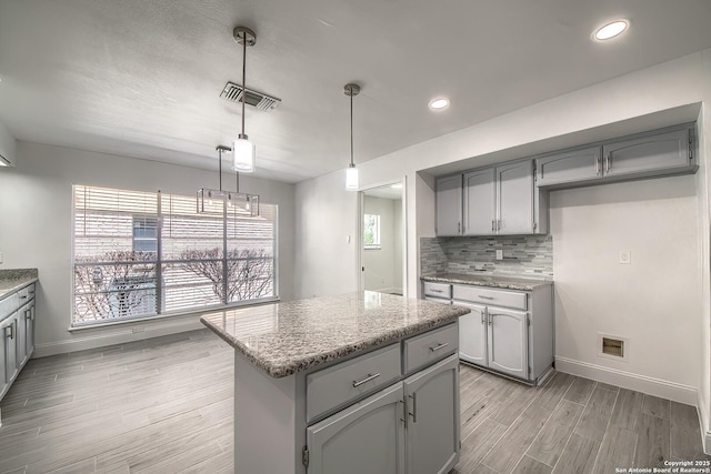 kitchen featuring light wood-style flooring, visible vents, backsplash, and gray cabinetry